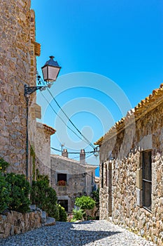 Narrow cobblestone wavy streets with potted tropical plants in the labyrinths of medieval Old Town of Tossa de Mar
