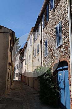 narrow deserted street where all the houses have shuttered windows to protect them from the heat of the sun