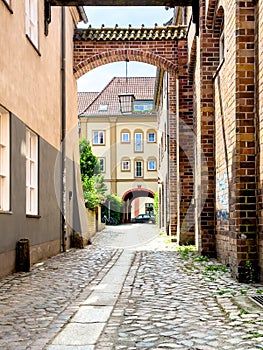 Narrow European street with brick buildings and paving stones.