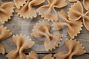 Narrow focus closeup of whole wheat farfalle pasta over wooden table