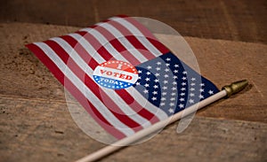 Narrow focus on I Voted Today paper sticker on US Flag
