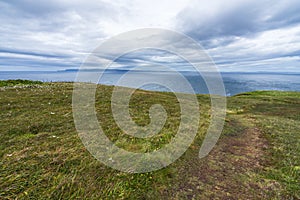 Narrow footpath on the coast of North Sea near Dunnet Head in Caithness, Scotland on a cloudy day