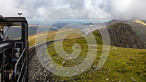 The narrow-gauge railway on Mount Snowdon with clouds and sun.