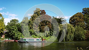 Narrow house boat cruising along the River Thames near Windsor. -  4k footage