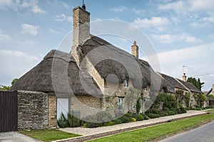 Narrow lane with romantic thatched houses and stone cottages in the lovely Minster Lovell village, Cotswolds, Oxfordshire