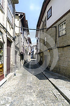 Narrow lonely alley with uneven cobblestone floor and Gothic style houses with stone facades in a village in Portugal called Guima