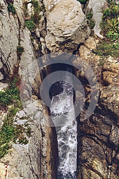 Narrow natural canal inside solid rocks with fierce water waves