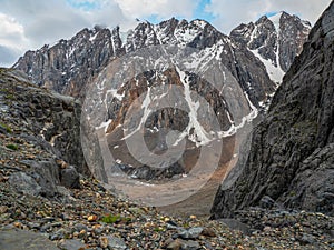 Narrow passage through the mountain couloir.Dangerous mountain couloir. Colorful sunny landscape with cliff and big rocky