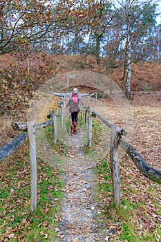 Narrow path between fences with mature woman walking with her dog
