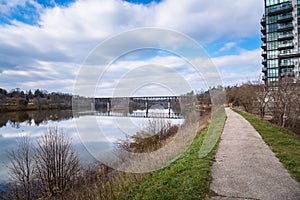 Narrow Path Running Alongside a River under Blue Sky with Clouds