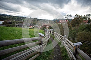 A narrow path between the wooden fences. Road leading down the mountain.