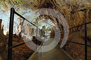 Narrow pathway between stalactites and stalagmites. Mystical view of Postojna Cave. Famous touristic place and romantic travel