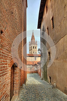 Narrow paved street among houses in Saluzzo.