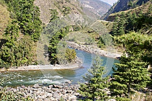 A narrow river flowing flanked by greenery on either side.