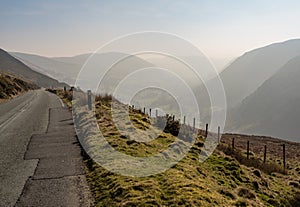 Narrow road besides misty valley in North Wales
