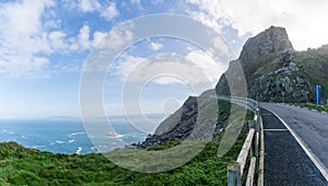 Narrow road leading along tall cliffs on a wild ocean coast