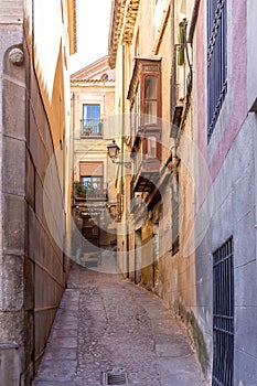 Narrow Spanish medieval cobbled street with old residential houses, Toledo, Spain.