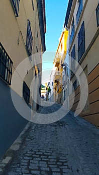 Narrow Spanish street, clear blue sky and cobbles.