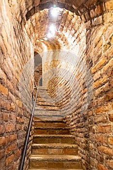 Narrow staircase in old cellar with brick walls