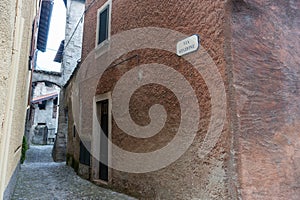 Narrow stony path between old buildings on Via Stazione, Como