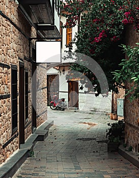 Narrow street in Antalyaâ€™s old town with rectangular billboard White mockup on the wall