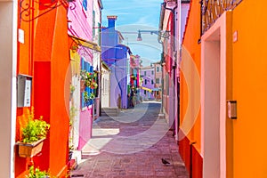 Narrow street with blue, red, green and purple house facade in the island of Burano, Venice