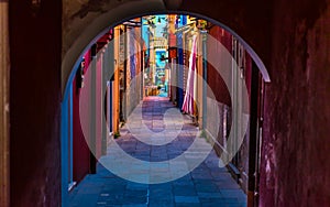 Narrow street with blue, red, green and purple house facade in the island of Burano, Venice