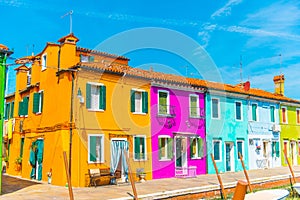 Narrow street with blue, red, green and purple house facade in the island of Burano, Venice