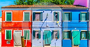 Narrow street with blue, red,and purple house facade in the island of Burano, Venice