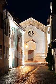 Narrow street with catholic church at night