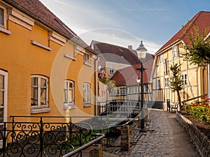 Narrow street with half-timbered houses along canal in Bogense, Funen, Denmark