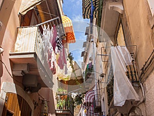 Narrow street with hanging clothes on balconies in south of Italy, Bari. Drying laundry on balcony. Italian southern architecture.