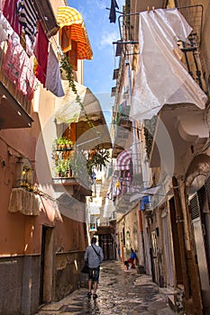 Narrow street with hanging clothes on balconies in south of Italy, Bari. Drying laundry on balcony. Italian southern architecture.