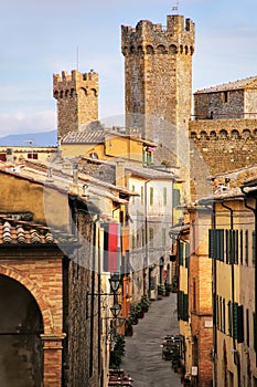 Narrow street in historic center of Montalcino town with fortre