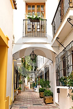 Narrow street and houses with arch in old town of Marbella, Spain
