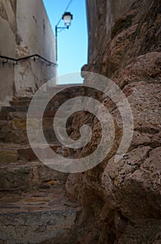 Narrow street with stairs up and a lamppost over the blue sky in the background, Onda, Castellon, Spain