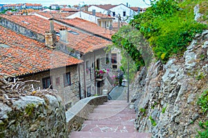 Narrow street with steps in San Vicente de la Barquera, Cantabria, Spain, with traditional stone houses at background