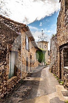 narrow street, stone houses and clock tower of an ancient village