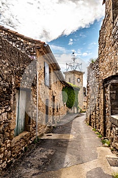 Narrow street, stone houses and clock tower of an ancient village