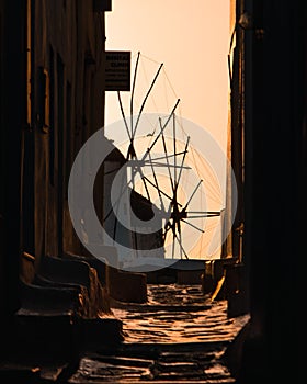 Narrow street with a view of windmills of Mykonos town in Greece