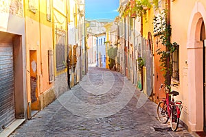 Narrow street of the village of fishermen San Guiliano with colorful houses and a bicycle in early morning in Rimini, Italy