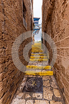 Narrow street of Yaffa with yellow step edges and Izraeli flag at the end photo