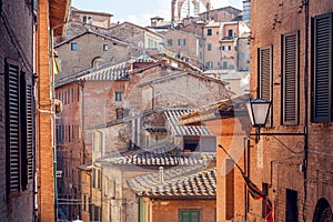 Narrow streets with historical houses of Siena, Tuscany. Tile roofs and brick structures in Italy. UNESCO Site