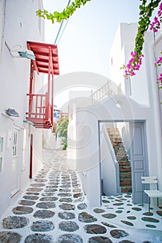 The narrow streets of the island with blue balconies, stairs and flowers in Greece.