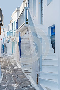 The narrow streets of the island with blue balconies, stairs and flowers. Mykonos, Greece.