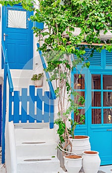The narrow streets of the island with blue balconies, stairs and flowers. Mykonos, Greece.