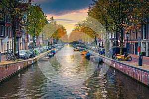 Narrow water canal with boats at sunset in Amsterdam, Netherlands