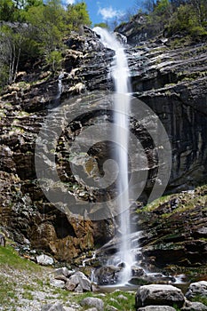 Narrow white stream of water flows over a wet stone cliff