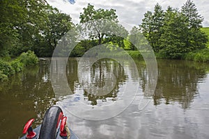 Narrowboat traveling on a British canal in rural setting