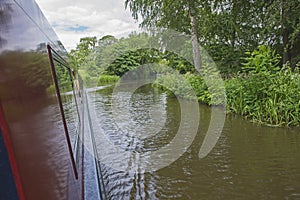 Narrowboat traveling on a British canal in rural setting